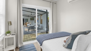 Un dormitorio con cama, puerta corrediza de vidrio que da a un patio y ventilador de techo.