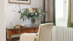 A room with a wooden desk, a chair, a framed picture on the wall, and a window with curtains. - Cozy One-Bedroom Apartment in the Heart of Florence (Firenze)