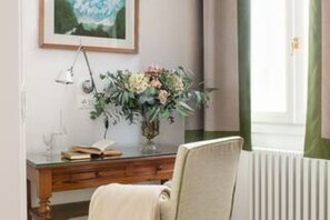 A room with a wooden desk, a chair, a framed picture on the wall, and a window with curtains. - Cozy One-Bedroom Apartment in the Heart of Florence (Firenze)