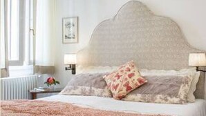 A bedroom with a large bed, two bedside lamps, a radiator, and a framed picture on the wall. - Cozy One-Bedroom Apartment in the Heart of Florence (Firenze)