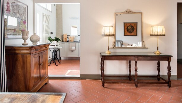 A hallway with a wooden cabinet, a green table with two lamps, and a mirror on the wall. - Cozy One-Bedroom Apartment in the Heart of Florence (Firenze)