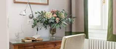 A room with a wooden desk, a chair, a framed picture on the wall, and a window with curtains.