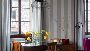 En matplats med ett glasbord, trästolar, en vas med gula blommor och en röd skål med en växt.