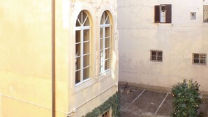 Ein Innenhof mit einem Gebäude, das gewölbte Fenster und einen kleinen Baum zeigt.