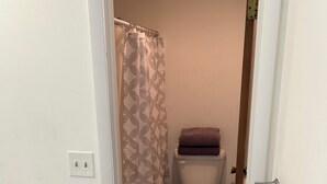 Un baño con inodoro, cortina de ducha y un perchero.