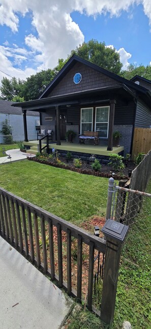 Ein Haus mit Veranda, einem kleinen Garten und einem Holzzaun.