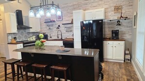 Una cocina moderna con una isla central, taburetes de madera, un refrigerador negro y una cafetera.