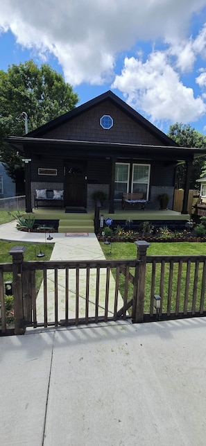 A two-story house with a porch, a welcome sign, and a bench.