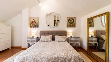 Un dormitorio con una cama grande, dos mesitas de noche, un aparador y un espejo grande.