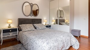 Ein Schlafzimmer mit einem großen Bett, zwei Nachttischen, einem Kleiderschrank und einem Spiegel.