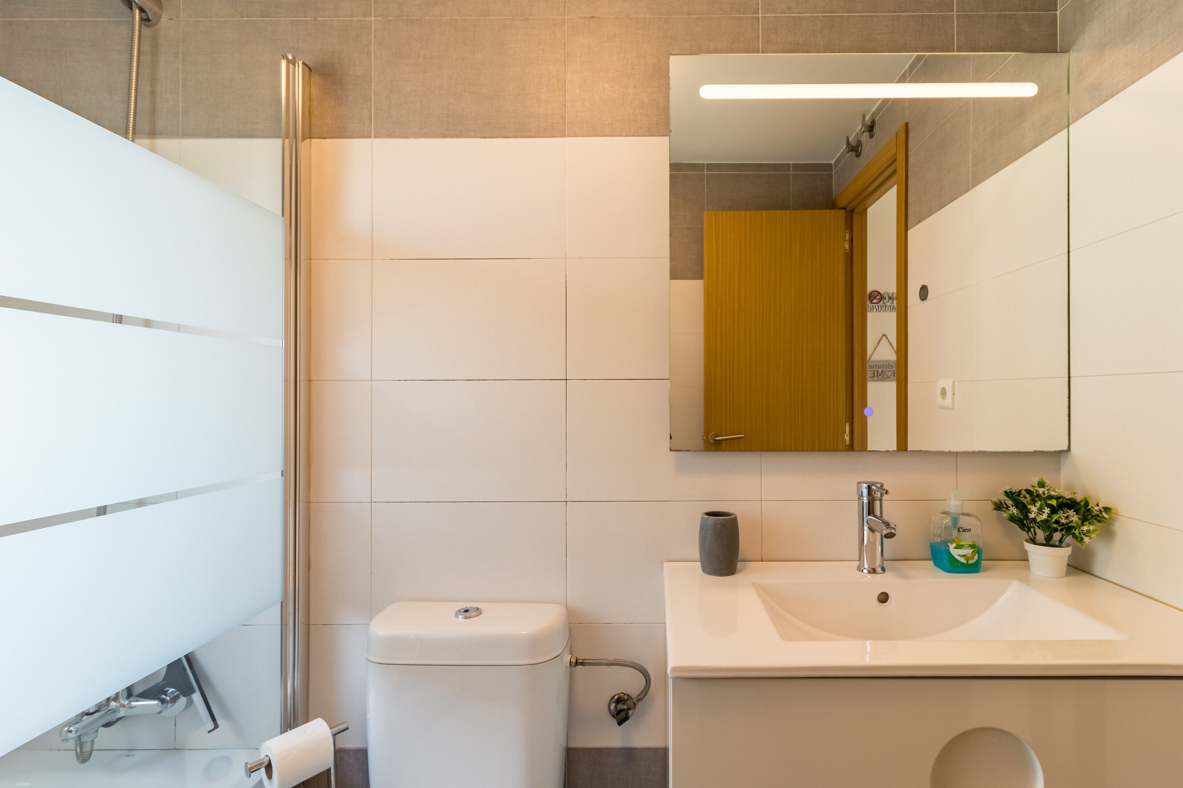 A modern bathroom with a glass shower enclosure, a white sink, and a mirror above the sink.