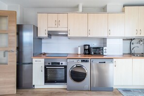 Une cuisine moderne dotée d’appareils électroménagers en acier inoxydable, de meubles en bois et d’un revêtement mural en carreaux.