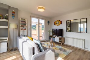Un salon moderne avec un canapé, un téléviseur et une grande fenêtre.