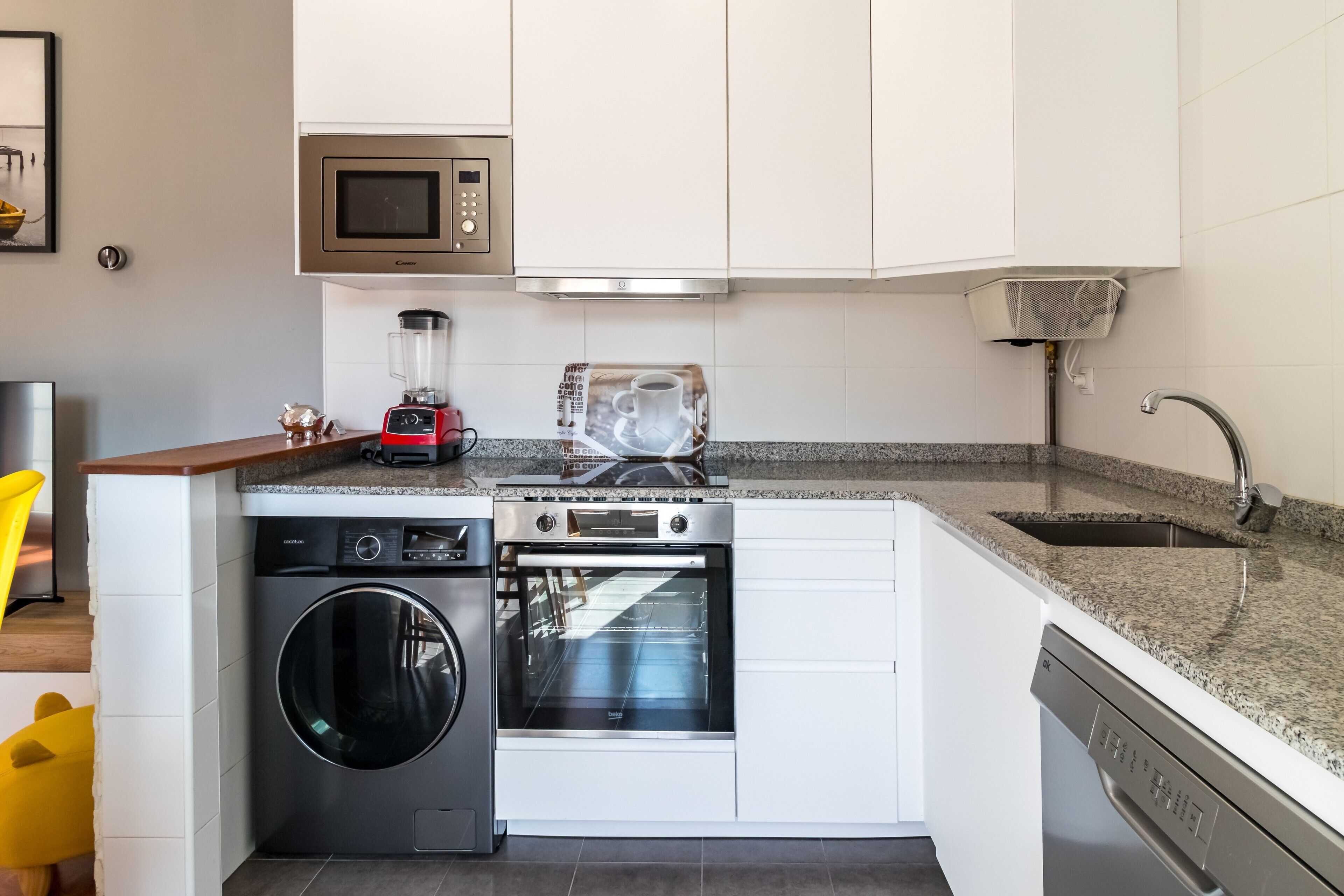 A compact kitchen with a washing machine, dishwasher, microwave, toaster, and a sink.