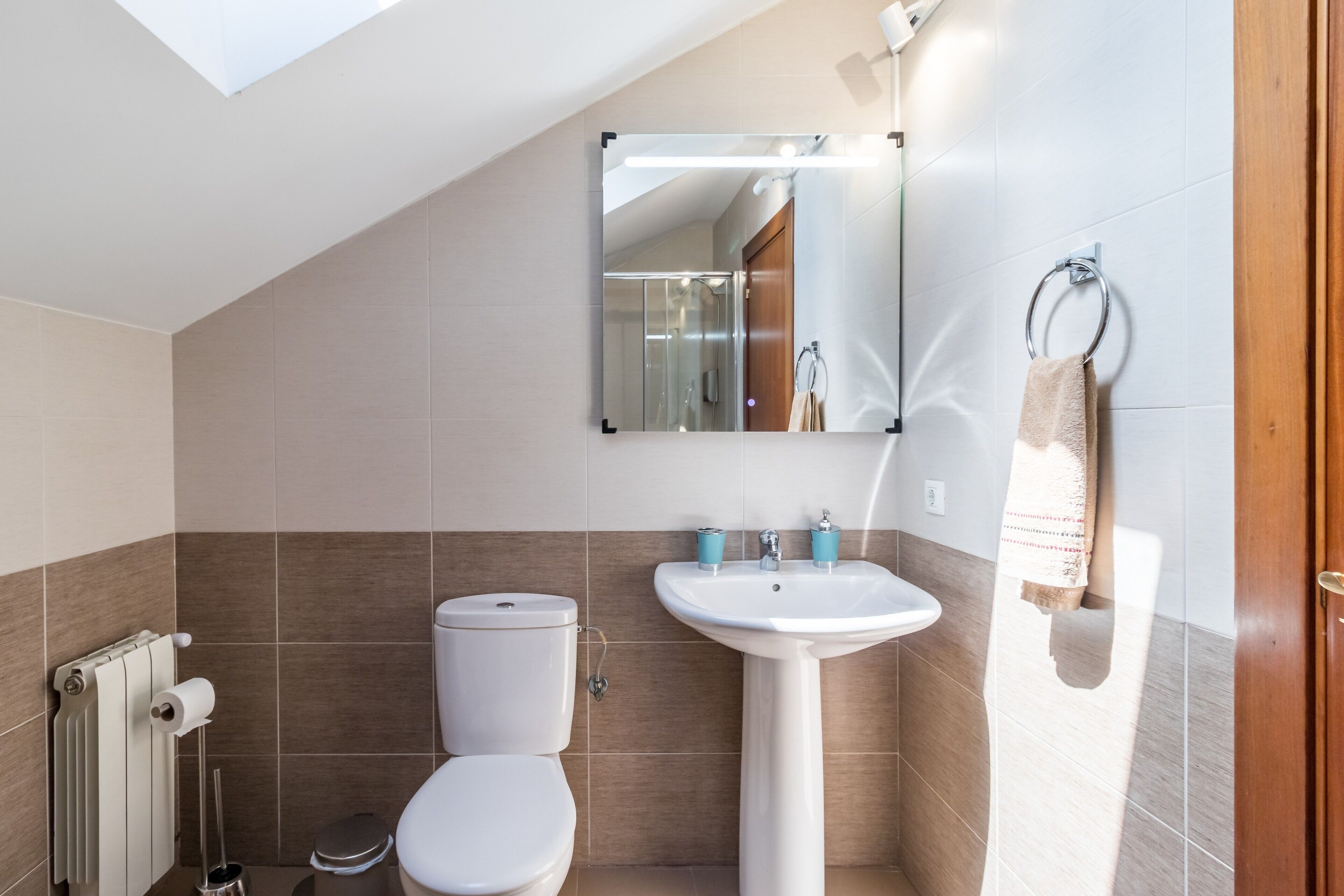 Ein modernes Badezimmer mit Oberlicht, Toilette, Waschbecken und Handtuchhalter.