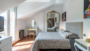 Un dormitorio con cama, cómoda, escritorio, espejo y un cuadro en la pared.
