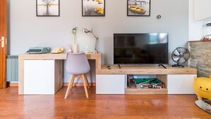 Una sala de estar moderna con un escritorio de madera, un televisor, una silla y obras de arte en la pared.