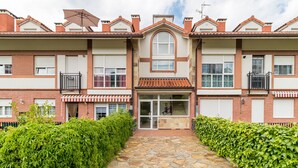 Un edificio residencial de varios pisos con entrada central, balcones y un sendero de piedra.