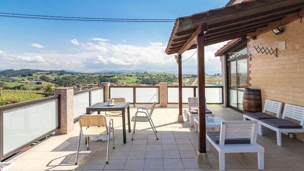 Una terraza con mesa, sillas y vistas al campo.