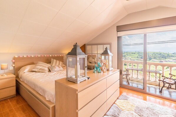 Une chambre avec un grand lit, des tables de chevet, une commode et un balcon aménagé avec du mobilier d’extérieur.