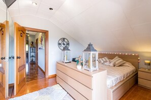 Une chambre à coucher comprenant un lit, des tables de chevet, une horloge et une porte donnant sur une autre pièce.
