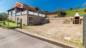 Una casa moderna con un patio de piedra, una chimenea de piedra y un cielo azul despejado.