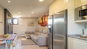 Una cocina moderna con un refrigerador de acero inoxidable, un microondas y un comedor con mantel colorido.