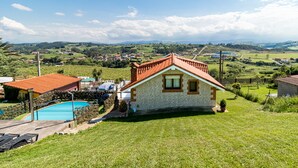 Una casa con piscina, rodeada de césped y un paisaje montañoso.