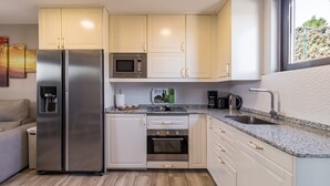 Una cocina compacta con refrigerador, microondas, horno y pileta.