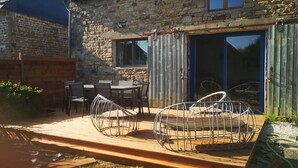 Un patio con piso de madera, sillas de metal y una mesa.