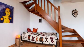 Un escalier en bois, un canapé avec des coussins à motifs et un tableau accroché au mur.