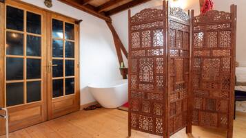 A room with wooden doors, a bathtub, and a decorative screen.