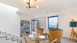 A dining area with a glass table, wicker chairs, a blue sofa, and a giraffe sculpture.