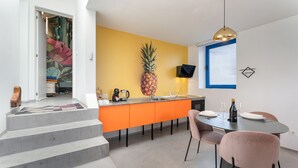 Eine moderne Küche mit gelber Akzentwand, einer Ananas-Dekoration und einem Essbereich mit rosa Stühlen.