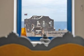 A view of a stone building with a flag, labeled 'HOTEL,' through a window with a blue frame. - Apartment 'Davide' with Balcony and Wi-Fi (Frontera)