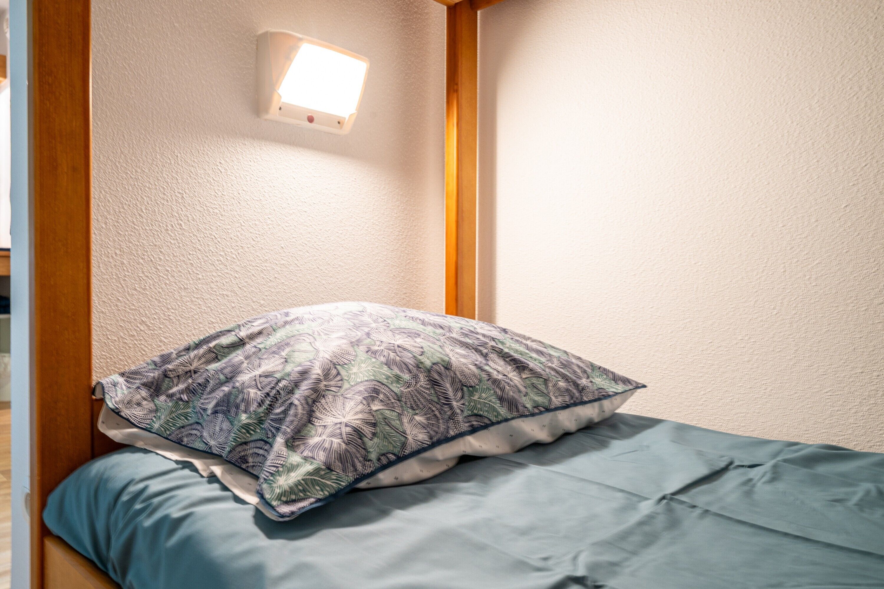 Ein Schlafzimmer mit einem Bett, einem Kissen, einer Wandleuchte und einem Holzkopfteil.