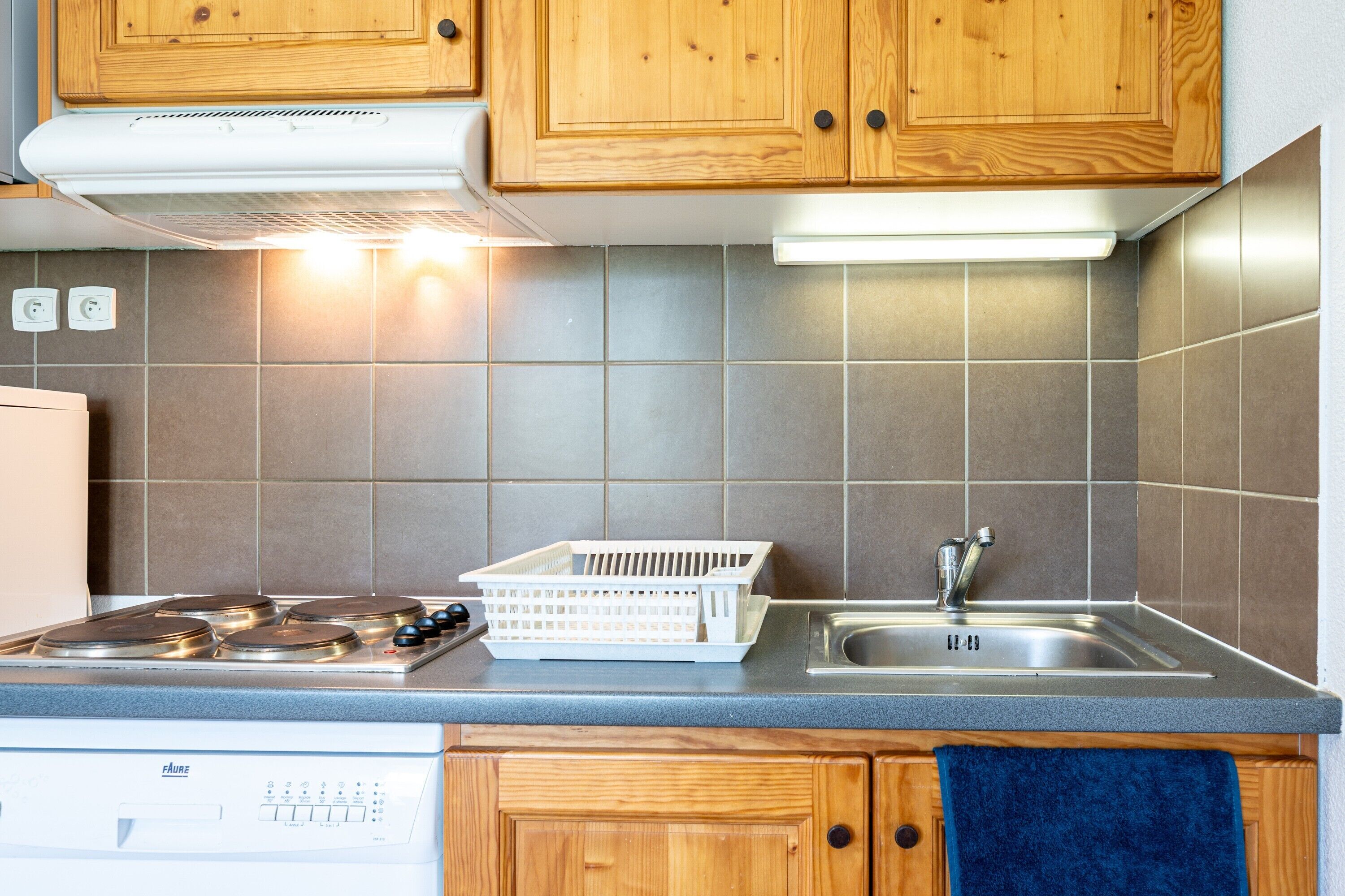 Une cuisine avec des meubles en bois, une cuisinière à gaz, un évier et un lave-vaisselle.