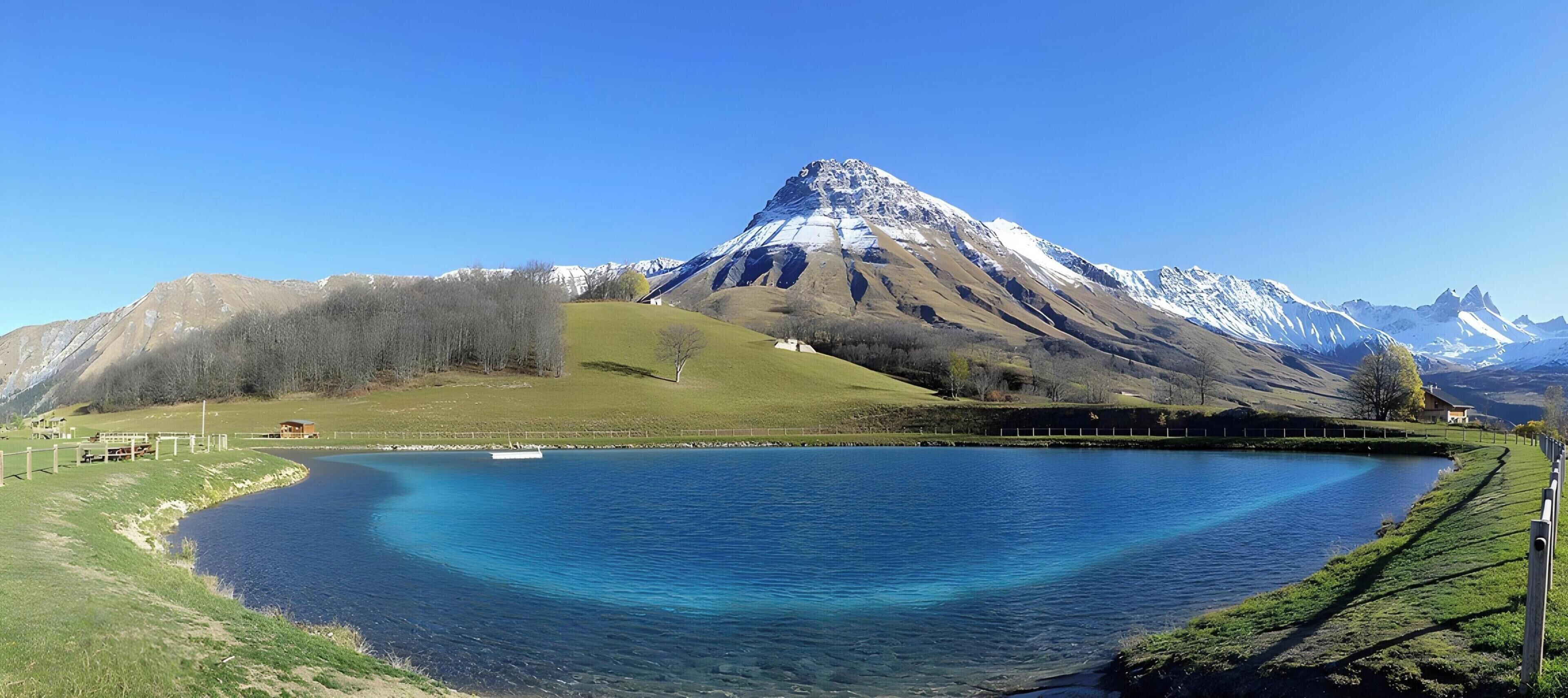 A mountain landscape with a lake, clear skies, and a fence.