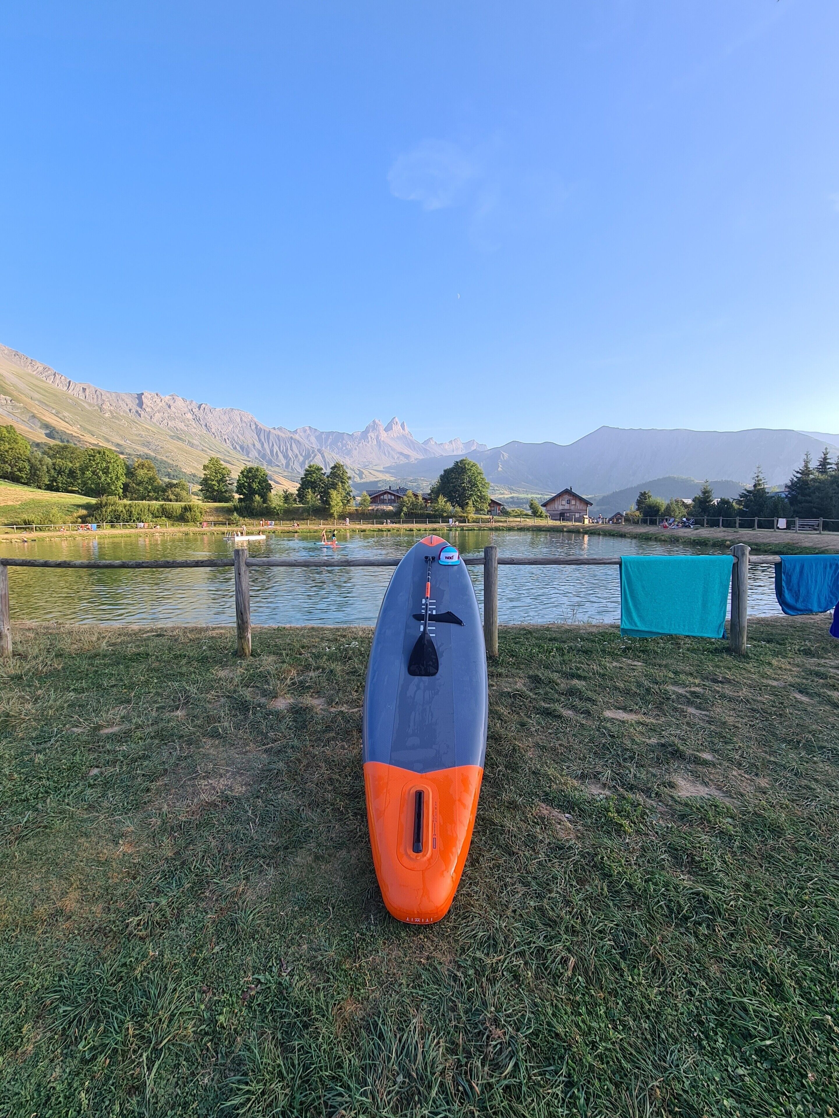 Un kayak sur une zone herbeuse près d’un lac, avec des montagnes en arrière-plan.