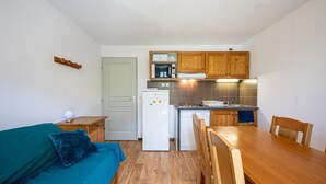 A compact kitchen with wooden cabinets, a refrigerator, microwave, and a dishwasher. - Apartment 'Neptune' with Mountain View and Balcony (Albiez-Montrond)