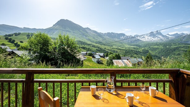 A wooden deck with a table and chairs, overlooking a mountainous landscape with houses. - Apartment 'Neptune' with Mountain View and Balcony (Albiez-Montrond)