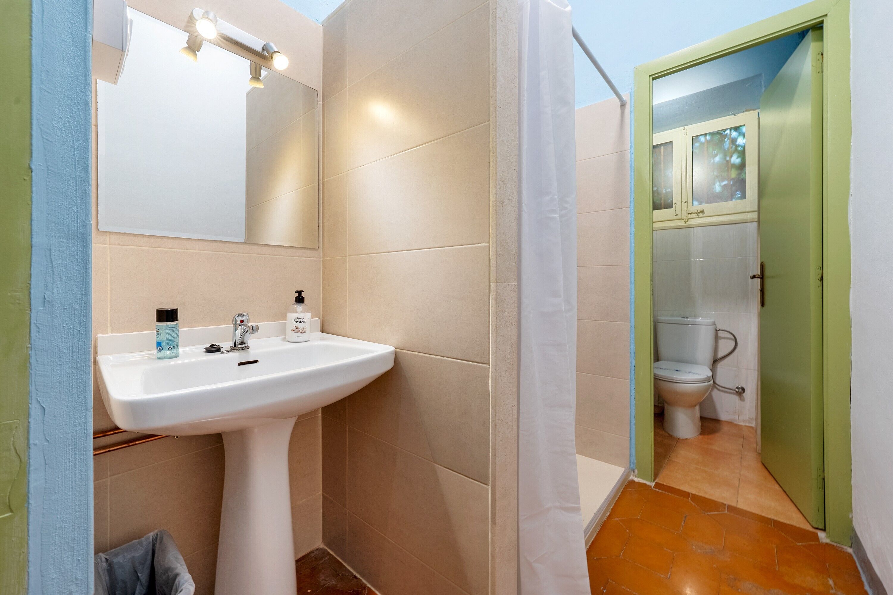 A bathroom with a white sink, mirror, and shower curtain.