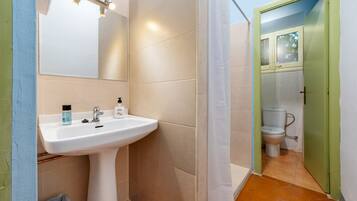 A bathroom with a white sink, mirror, and shower curtain.
