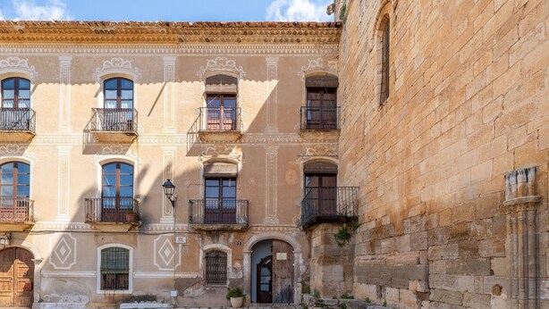 Un edificio histórico con varios balcones, un patio empedrado y una entrada tradicional.