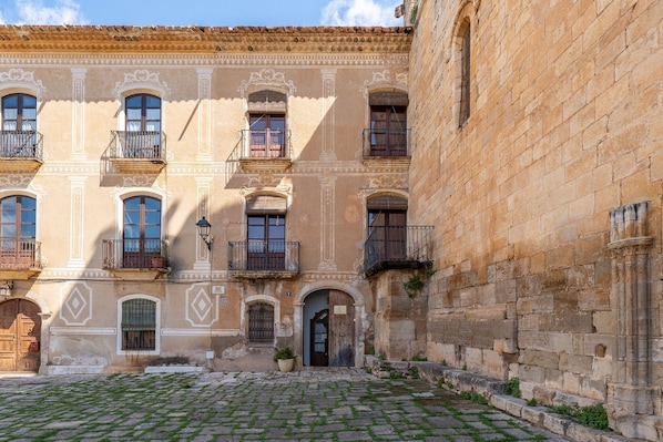 A historic building with multiple balconies, a cobblestone courtyard, and a traditional entrance.