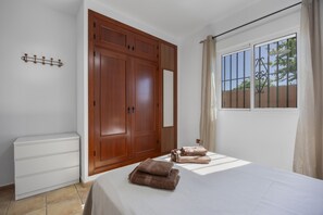 A bedroom with a bed, a wardrobe, a mirror, and a window with curtains.