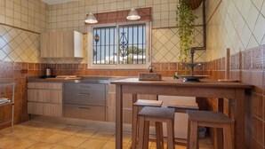 A kitchen with wooden cabinets, a tiled backsplash, a window with bars, and a hanging plant.