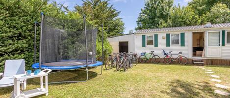 A house with a trampoline, bicycles, and a small outdoor seating area.