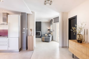 A modern kitchen with white cabinets, a built-in oven, and a dining area with a wooden table and chairs.