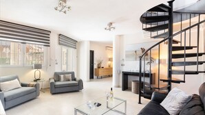 Un salon moderne avec une table basse en verre, deux canapés, une cheminée et un escalier en colimaçon.